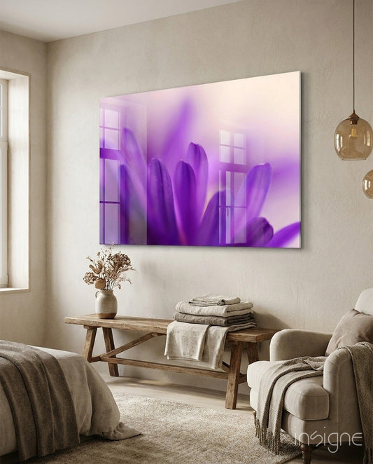 Purple daisy glass wall art hung above wooden bench in neutral bedroom with cream armchair and pendant lights.