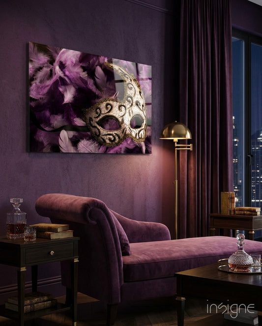Ornate gold and cream venetian mask with purple feathers displayed on purple wall above velvet chaise lounge in luxury interior setting.