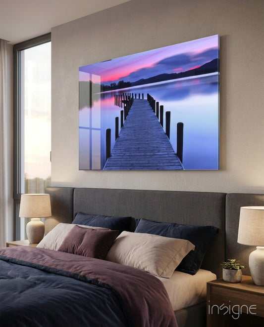 Purple Twilight Mountain Jetty Glass Wall Art mounted above bedroom headboard, displaying wooden dock extending into reflective water at sunset.
