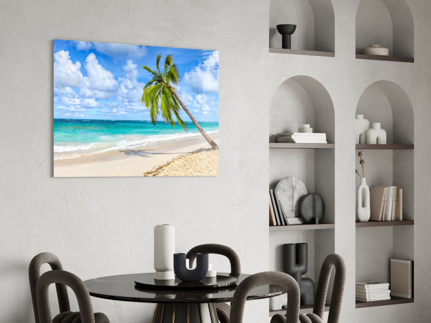 Tropical beach scene with palm tree, turquoise ocean, and white sand displayed as glass wall art above dining table.