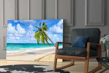 Tropical beach glass wall art featuring palm tree and turquoise ocean displayed next to wooden chair in modern room.