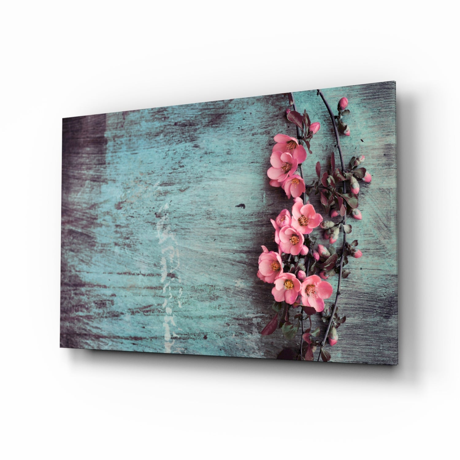 Angled view of glass wall art featuring pink flowers on green weathered wood background with shadow effect.