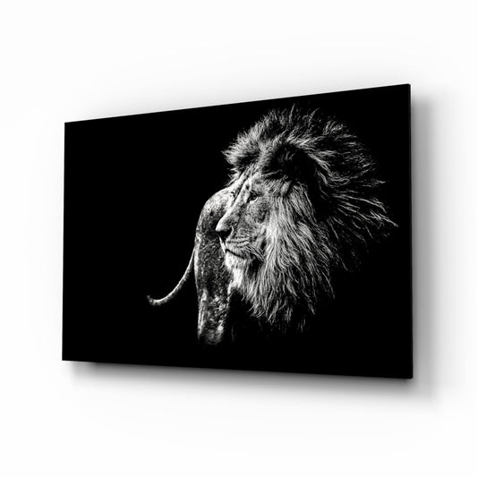 Black and white portrait of a lion's head in profile facing left, displayed on a glass wall panel against a light background.