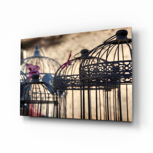 Three decorative black birdcages with ornate details casting shadows on a neutral beige wall background.
