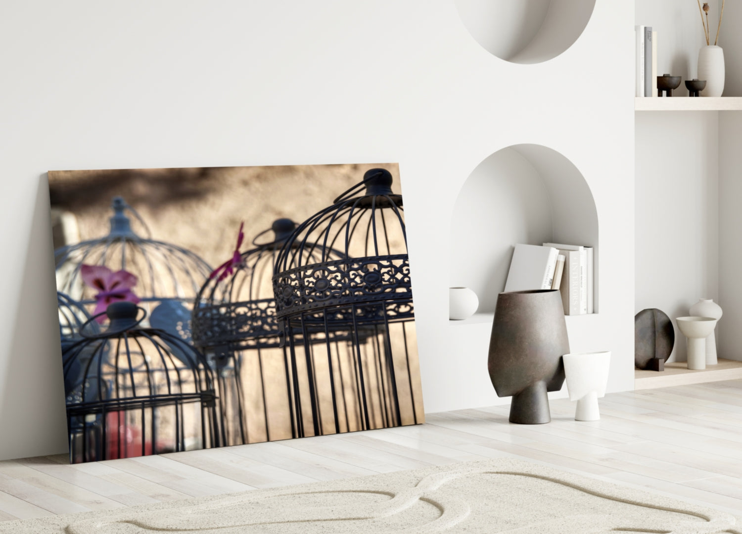 Birdcage glass wall art leaning against white wall in minimalist room with decorative objects and sand patterns.