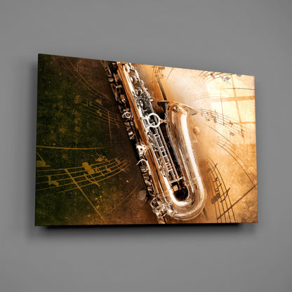 Angled view of glass wall art featuring a silver saxophone against a sepia-toned background with musical notes and sheet music motifs.