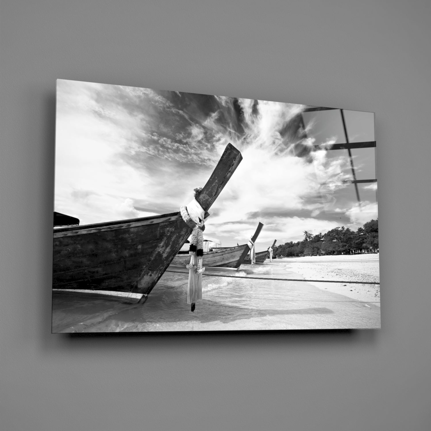 Black and white glass wall art featuring traditional longtail boats beached on sand with dramatic cloudy sky.