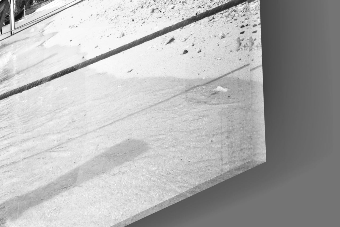 Close-up detail of textured concrete surface with dark dividing line and small stones embedded in light gray material.