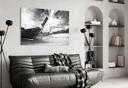 Black and white glass wall art of beached boats displayed above a gray leather sofa in a modern living room interior.