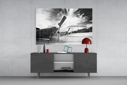 Black and white photograph of traditional long-tail boats on water displayed above dark gray media console with red decorative accessories.