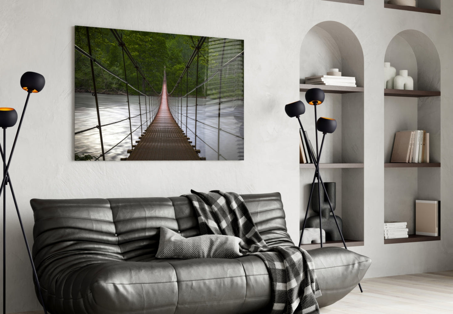 Suspension bridge glass wall art hung above black leather sofa in modern living room with arched shelving.