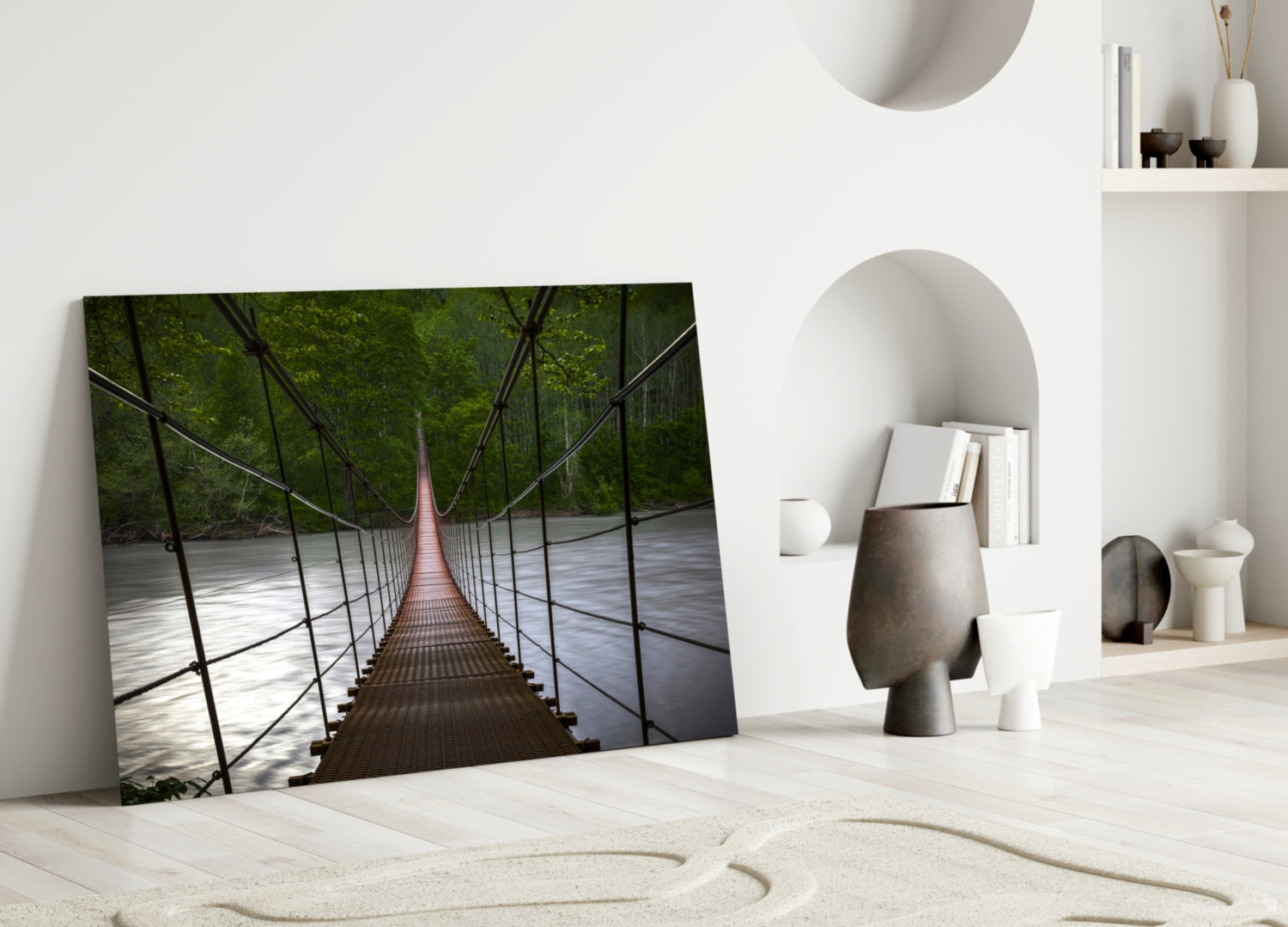 Suspension bridge glass wall art leaning against white wall in minimalist room with sand and decorative objects.