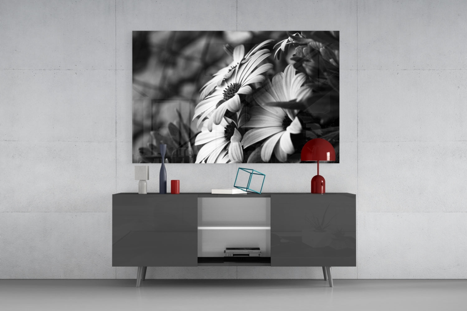 Black and white daisy flowers with red accent displayed on wall above gray media console in modern living room setting.