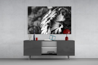 Black and white daisy flowers with red accent displayed on wall above gray media console in modern living room setting.