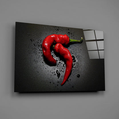 Angled view of red pepper glass wall art on gray background with water droplets and grid pattern visible on right edge.