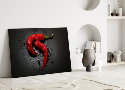 Red pepper glass wall art leaning against white wall in minimalist interior setting with decorative objects.