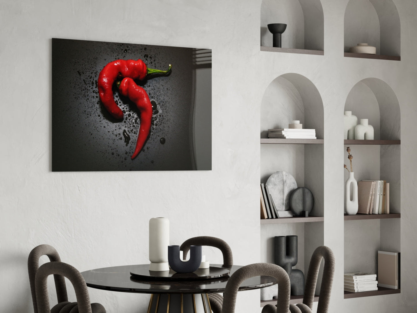 Red pepper glass wall art hanging above a black dining table in a modern interior with white shelving.