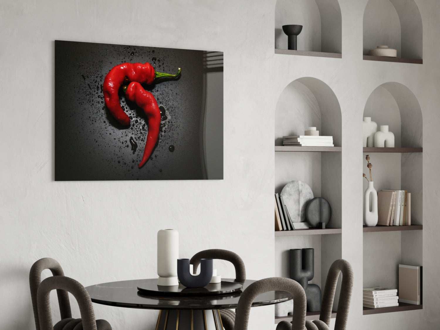 Red pepper glass wall art hanging above a black dining table in a modern interior with white shelving.