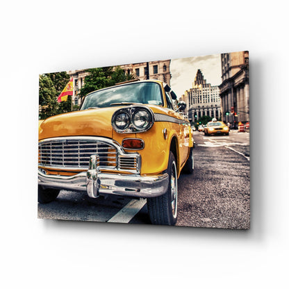 Yellow vintage taxi cab with chrome details on an urban street, displayed as a glass wall art panel with 3D perspective shadow effect.