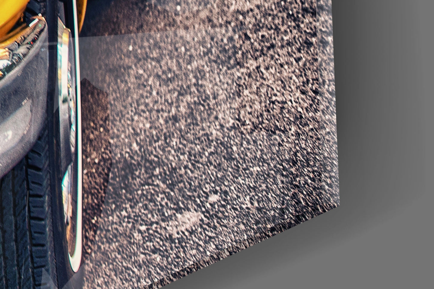 Close-up of yellow taxi door and chrome trim against dark asphalt road surface with shadows.