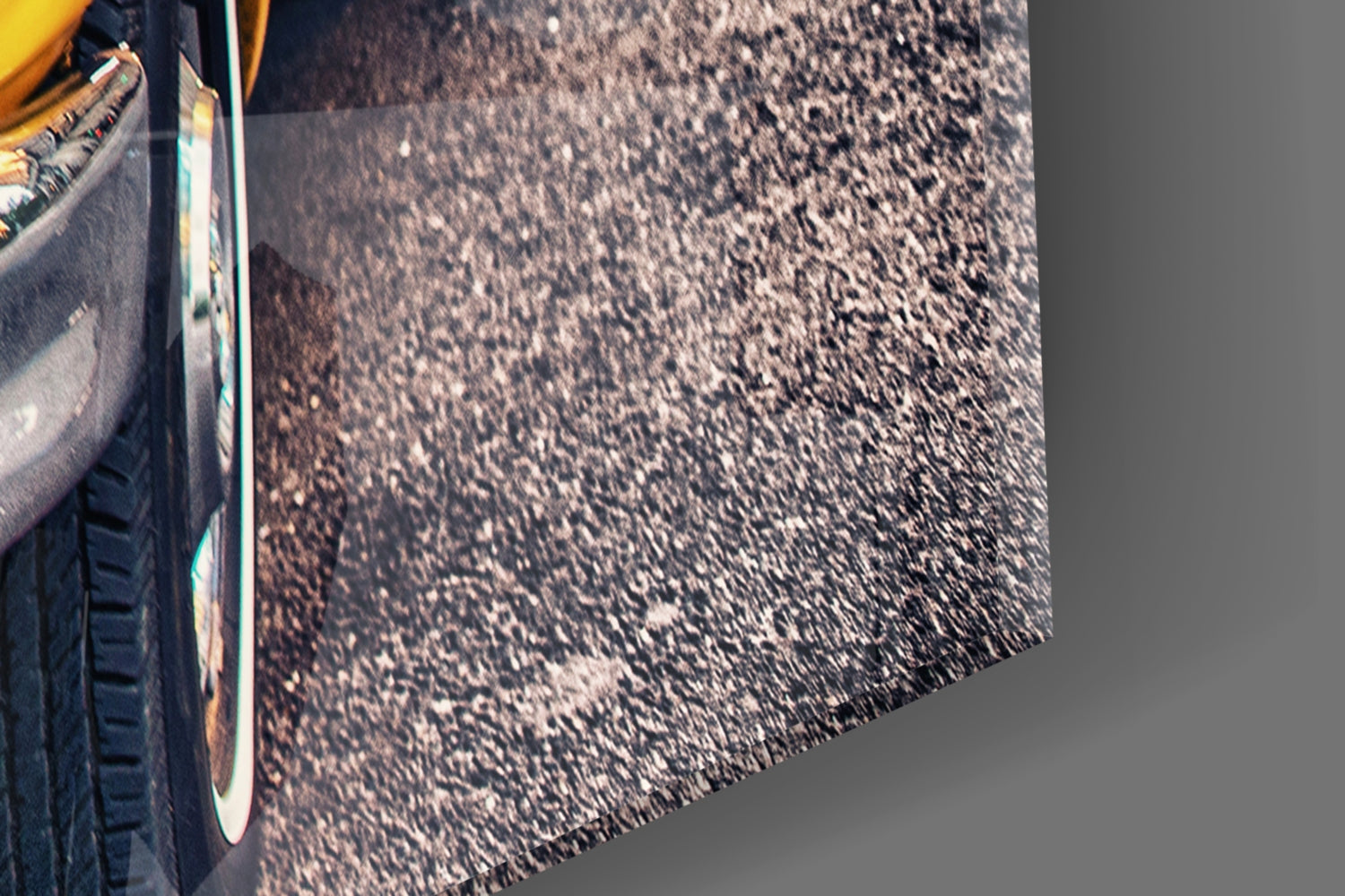 Close-up of yellow taxi door and chrome trim against dark asphalt road surface with shadows.