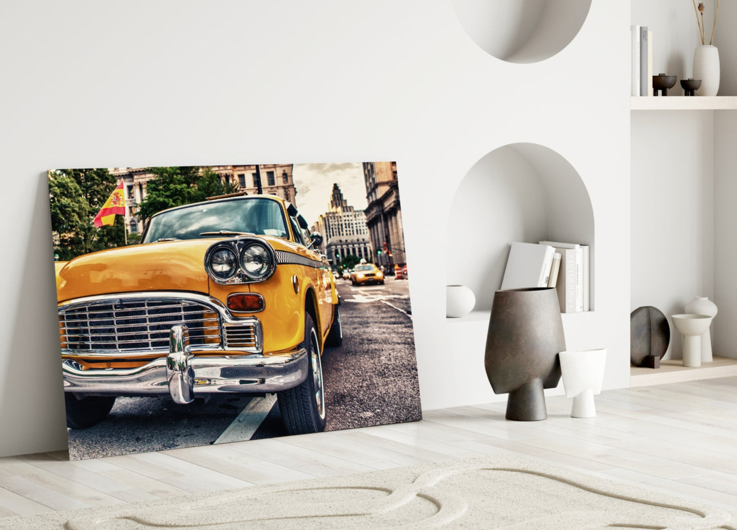 Classic yellow taxi glass wall art leaning against white wall in minimalist room setting with decorative objects.