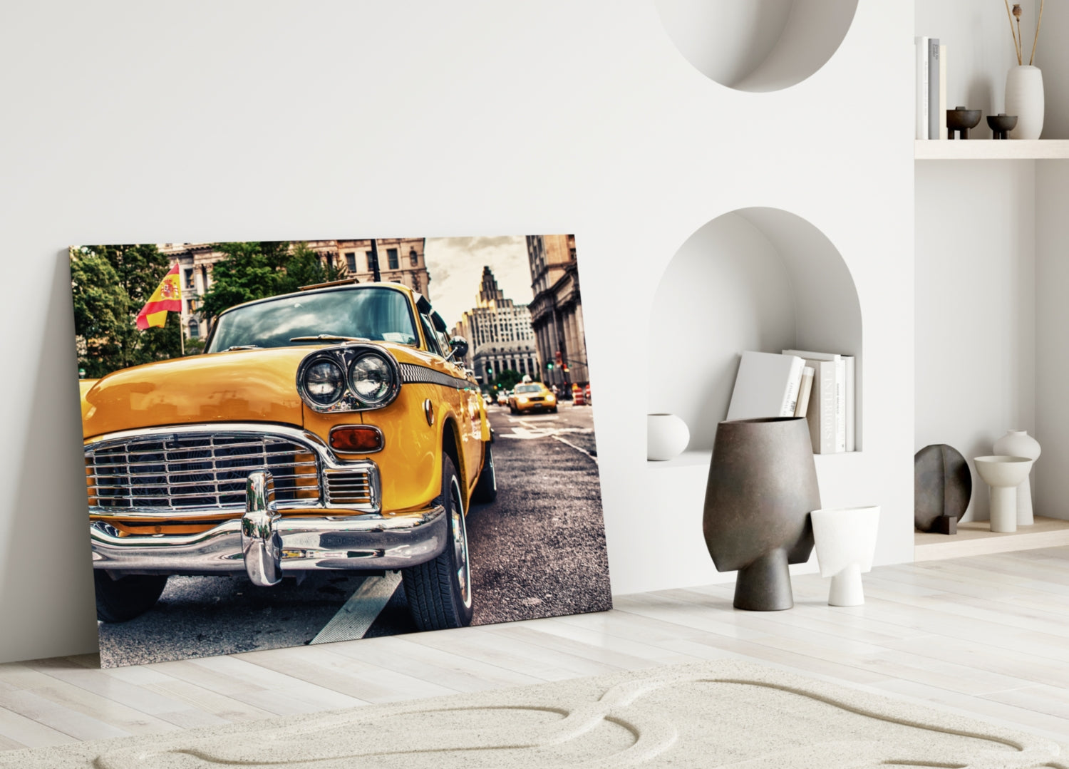Classic yellow taxi glass wall art leaning against white wall in minimalist room setting with decorative objects.