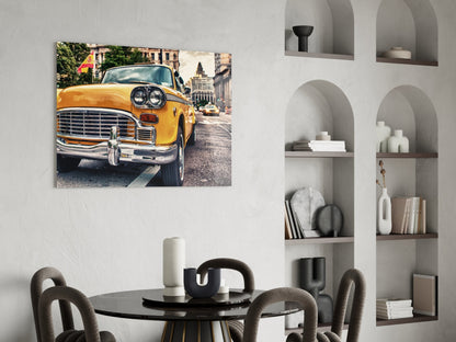 Yellow vintage taxi cab on urban street displayed as glass wall art above dining table in modern interior.