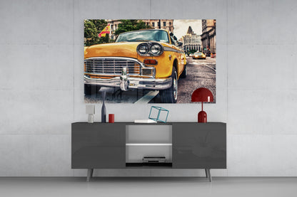 Yellow vintage taxi displayed as glass wall art above a gray media console with decorative items.