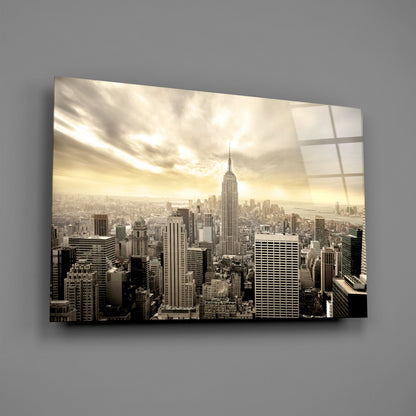 Sepia-toned Manhattan skyline featuring the Empire State Building centered among surrounding skyscrapers, printed on glass wall art with visible grid overlay.