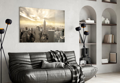 New York City glass wall art showing sepia-toned skyline with Empire State Building displayed above black leather sofa in modern living room.