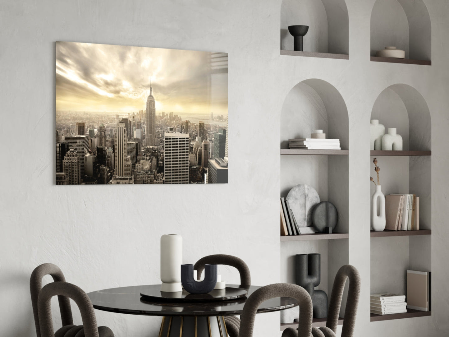 New York City glass wall art showing Manhattan skyline with Empire State Building displayed above a black dining table in a modern interior with built-in wall shelving.