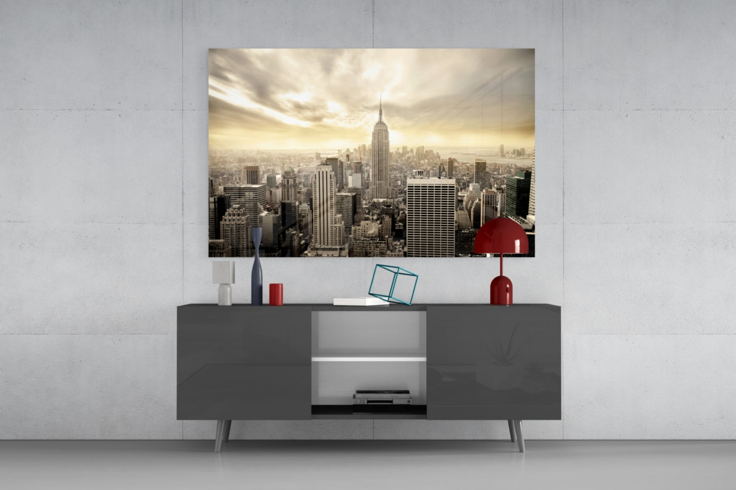 Sepia-toned NYC skyline glass wall art displayed above dark gray media console with red decorative accessories.