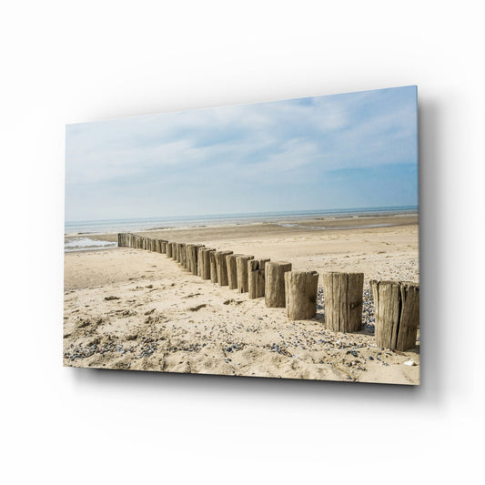 Angled view of canvas print showing wooden posts receding along sandy beach toward calm sea under blue sky.