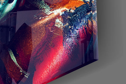 Angled perspective view of illuminated glass wall art displaying abstract female portrait in vibrant red, orange, teal, and dark blue tones.