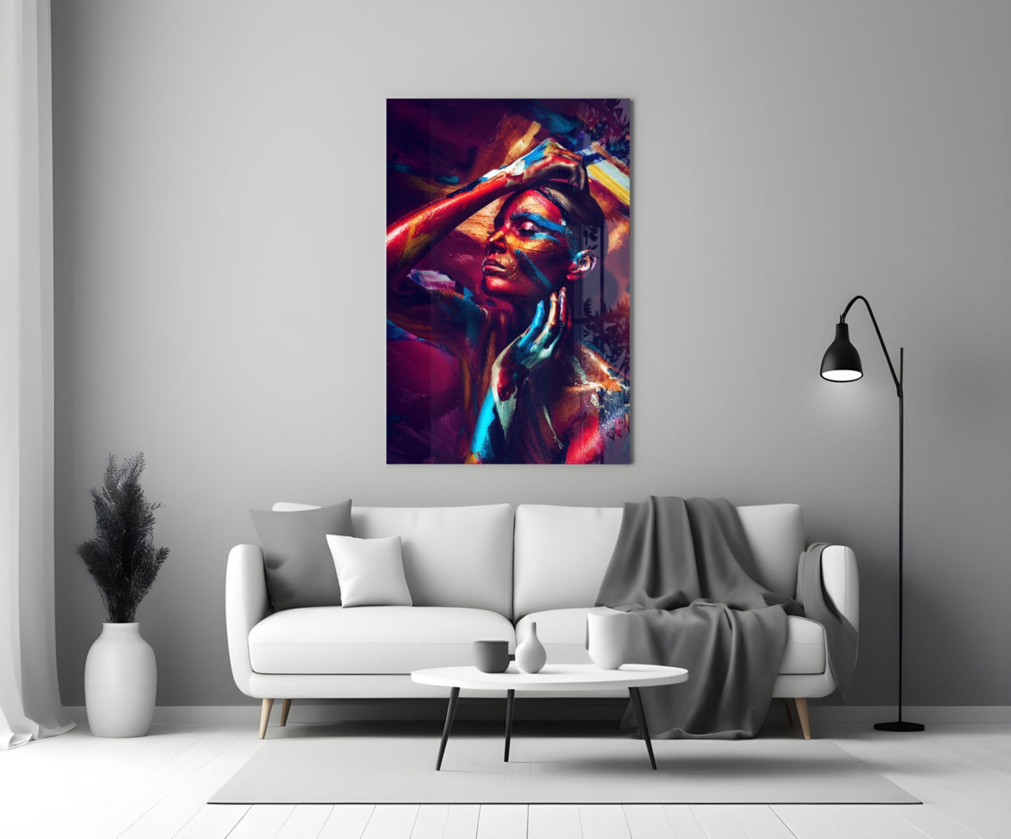 Colorful glass wall art featuring a woman's portrait with vibrant red, blue, and yellow light effects displayed above a white sofa.