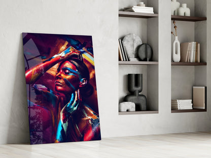 Vibrant glass wall art featuring a colorful portrait of a woman in neon red, blue, and gold tones, leaning against white wall shelving.