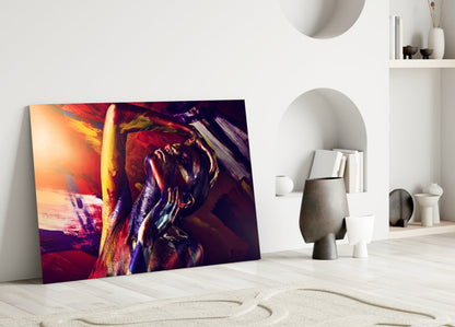 Colorful glass wall art depicting an abstract woman portrait in vibrant reds, golds, and purples, displayed leaning against a white wall in a minimalist interior.