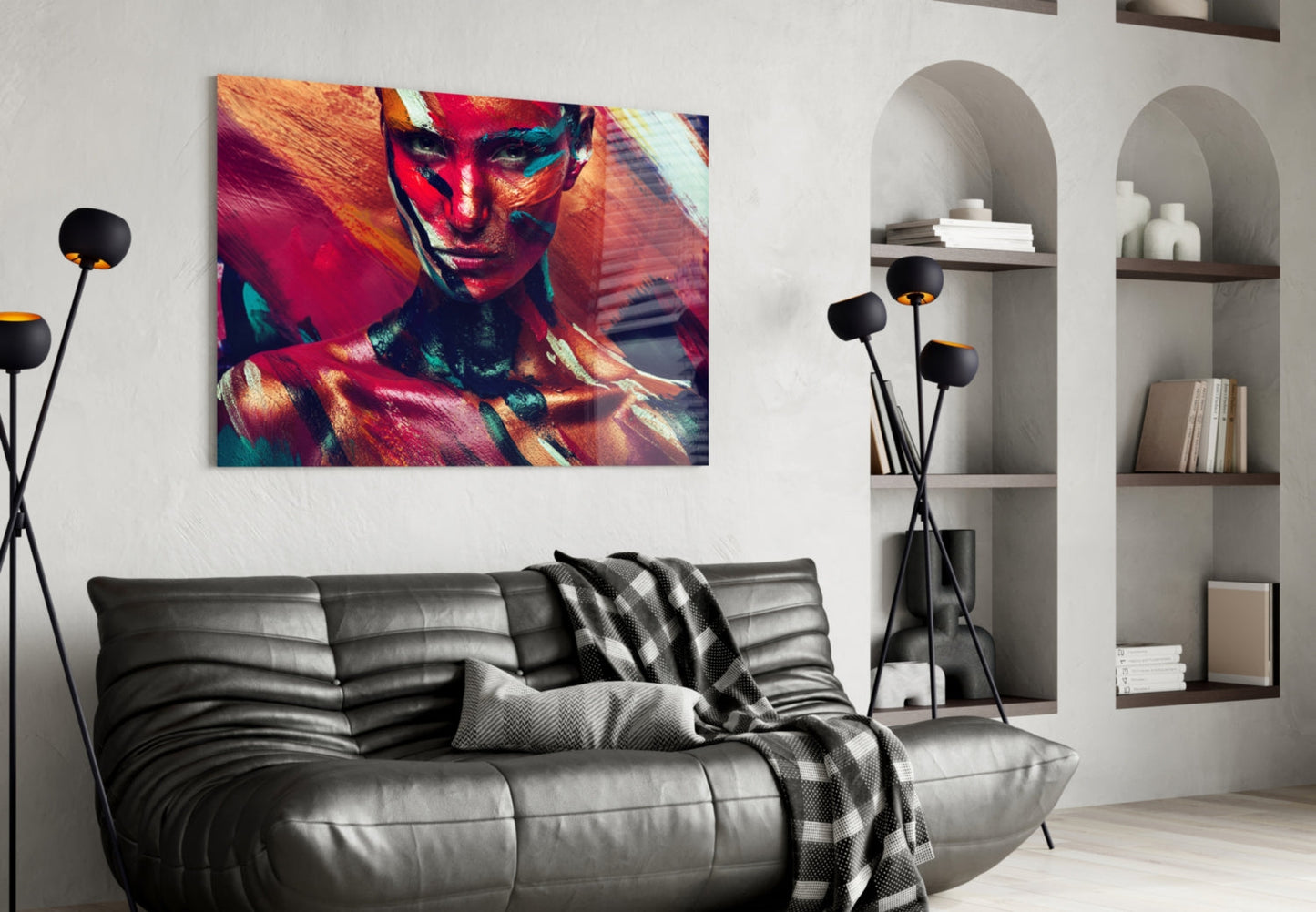 Vibrant glass wall art featuring a colorful portrait of a woman with red, gold, and teal paint effects, displayed above a black leather sofa in a modern living room.
