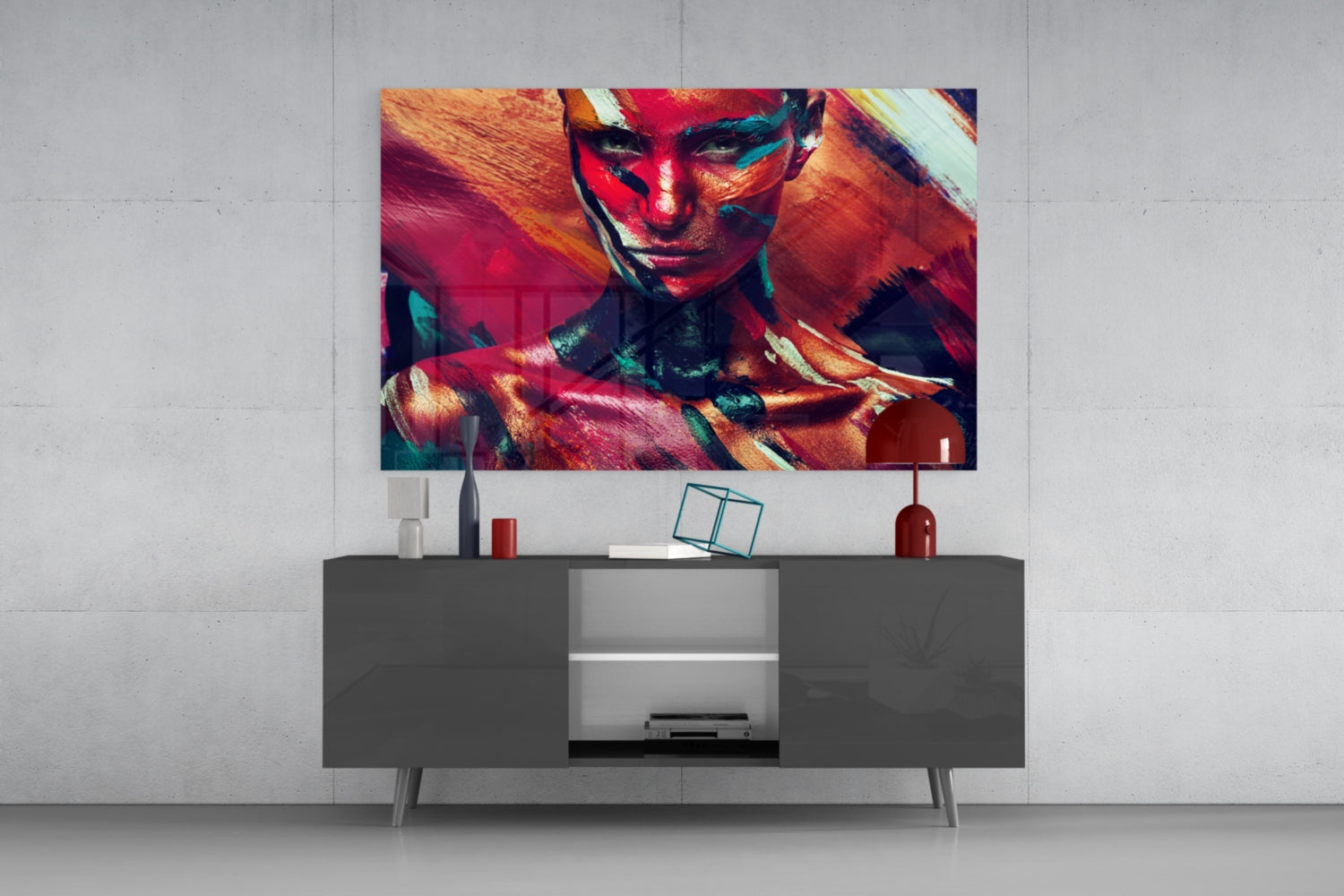 Colorful glass wall art featuring a woman's portrait with red, orange, and teal paint effects displayed above a modern gray media console.