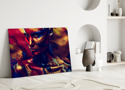 Vibrant glass wall art depicting a colorful female portrait with red, gold, and blue tones leaning against white interior wall.