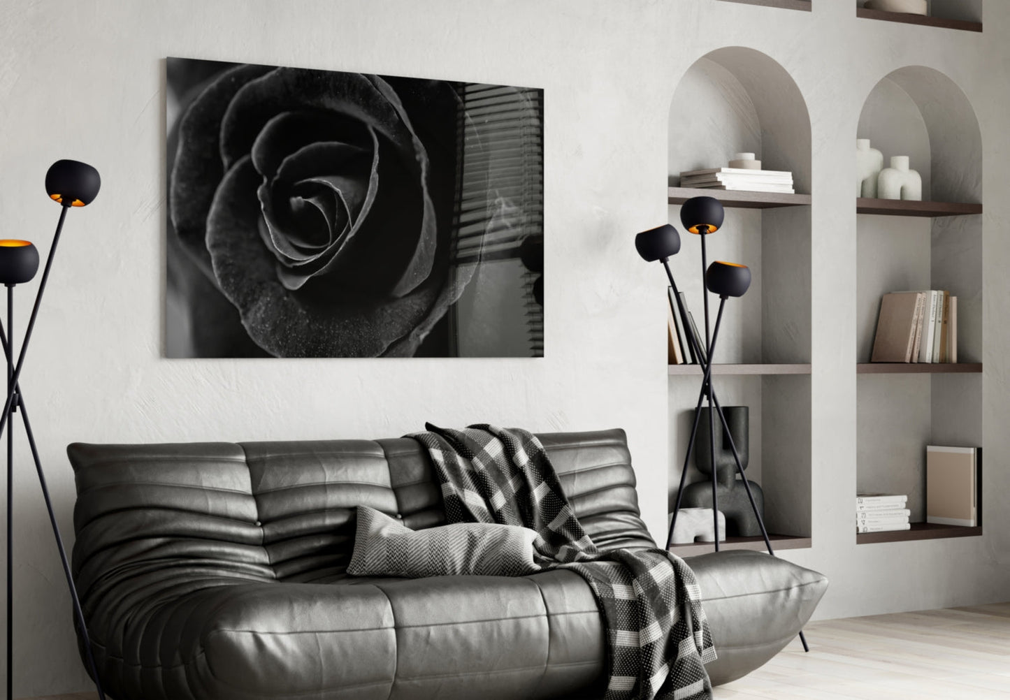 Black rose glass wall art displayed above a gray leather sofa in a modern living room with shelving.