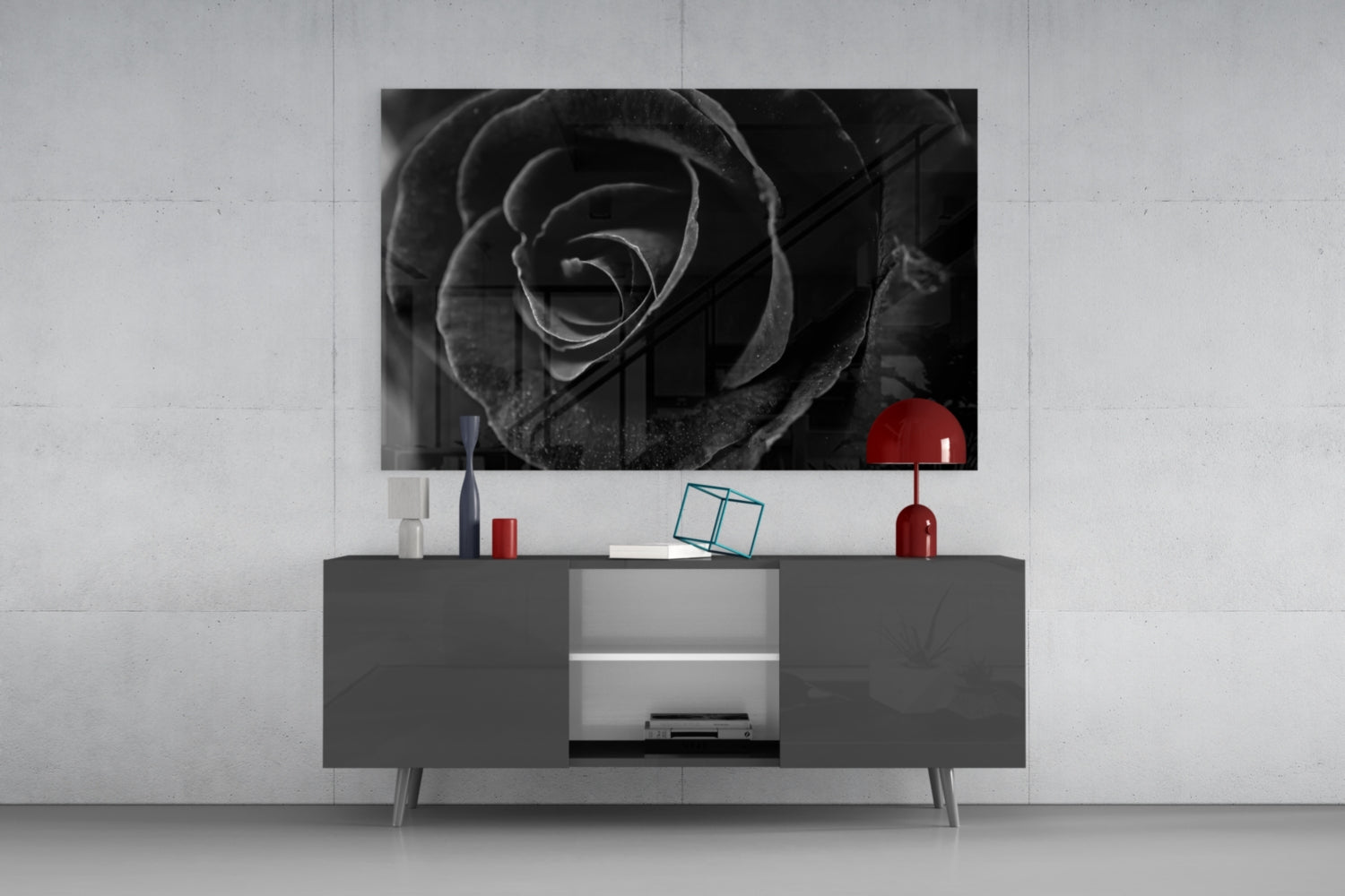 Black and white rose photograph displayed on wall above gray media console with red decorative accessories.