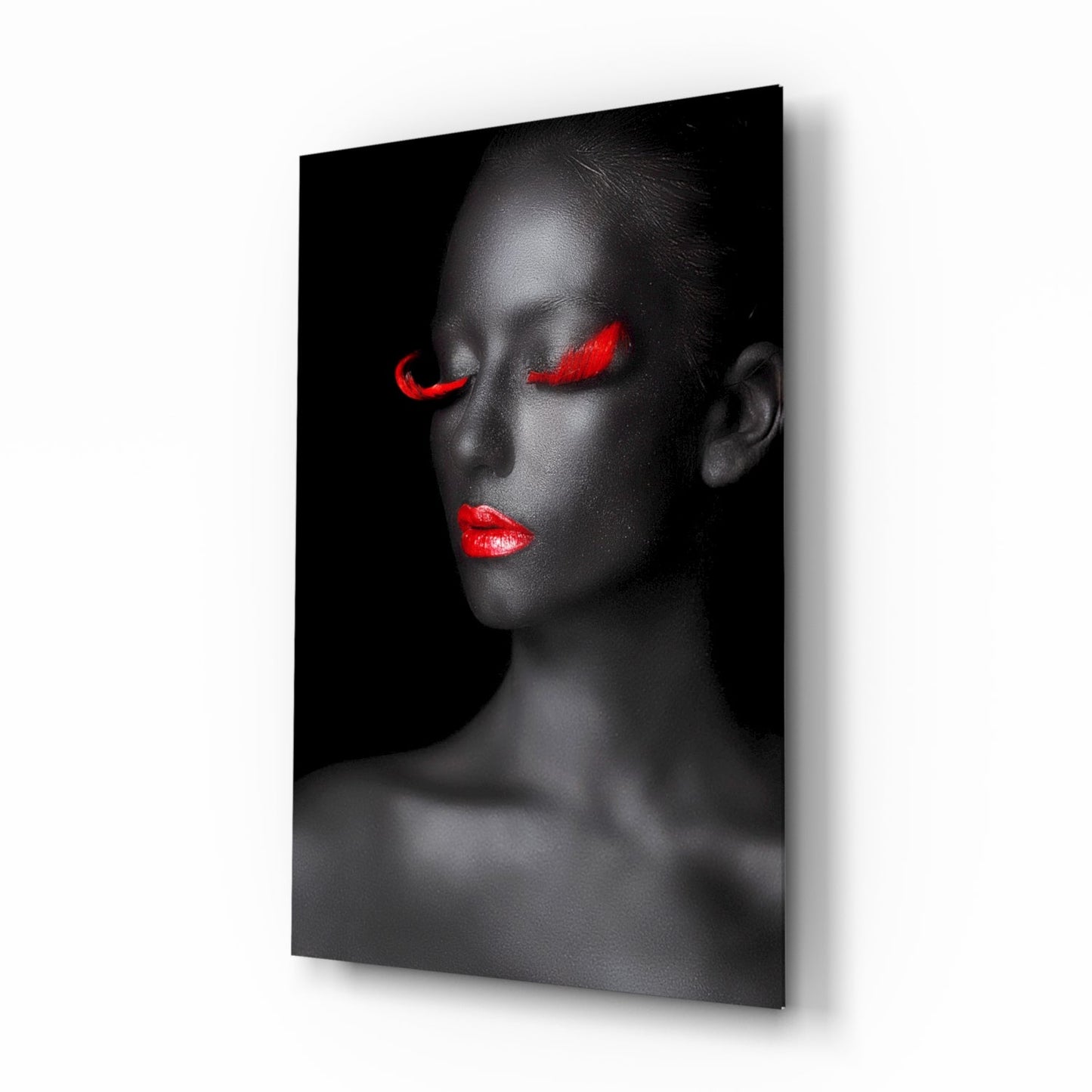Profile view of a woman's face with closed eyes and bright red lips and eyeshadow against black background on glass wall art.