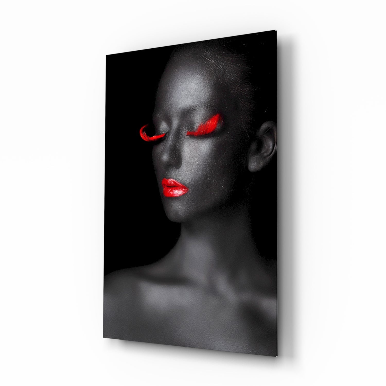 Profile view of a woman's face with closed eyes and bright red lips and eyeshadow against black background on glass wall art.