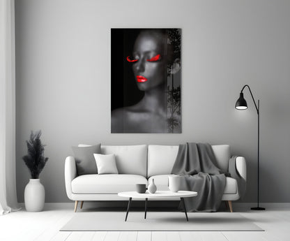 Woman portrait glass wall art with grayscale face and glowing red eyes and lips, displayed above white sofa in modern living room.