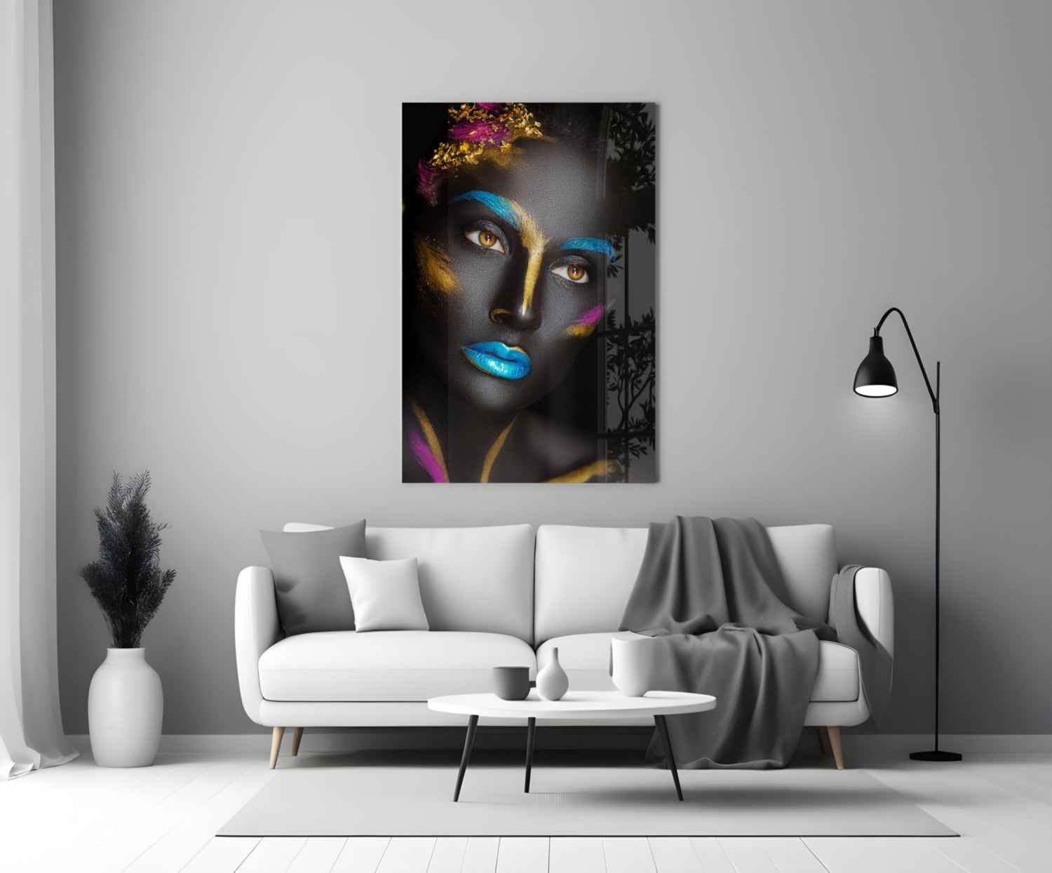 Glass wall art depicting a woman's face with dark skin, blue and gold paint, striking amber eyes, displayed above a white sofa in a modern living room.