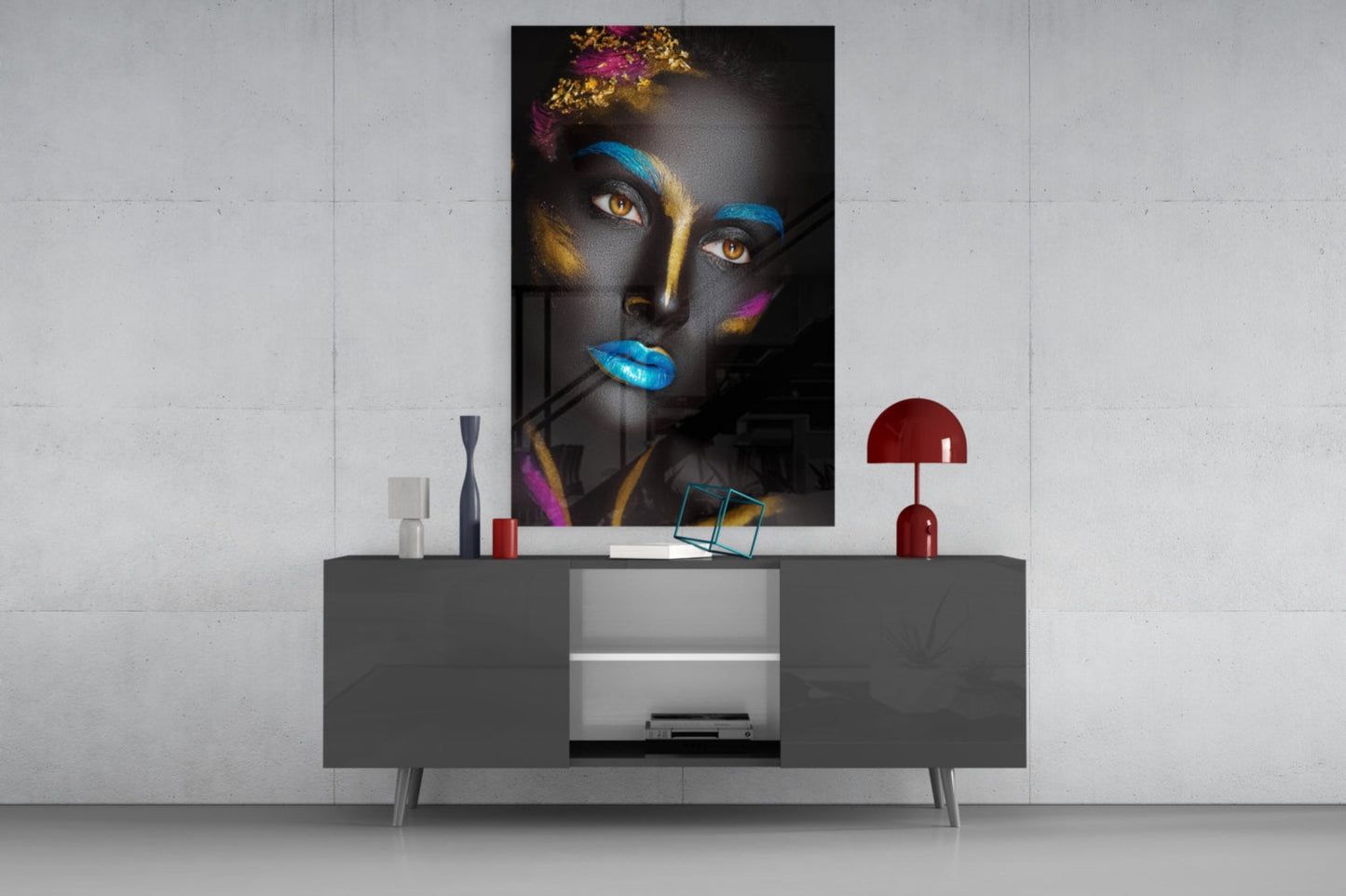 Modern living room display featuring glass wall art of a woman's face with gold, blue, and purple paint details mounted above a gray media console.