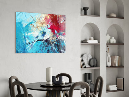 Colorful abstract glass wall art with blue, red, and yellow splatter design displayed above a dining table in a modern interior.
