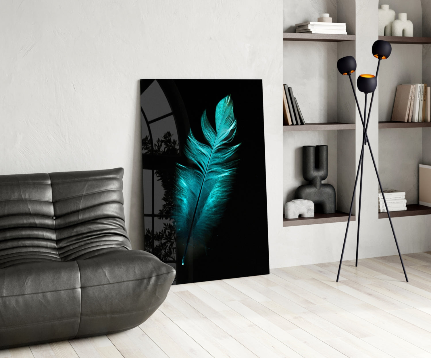 Glowing turquoise feather artwork displayed on black glass leaning against white wall beside gray leather chair and shelving.